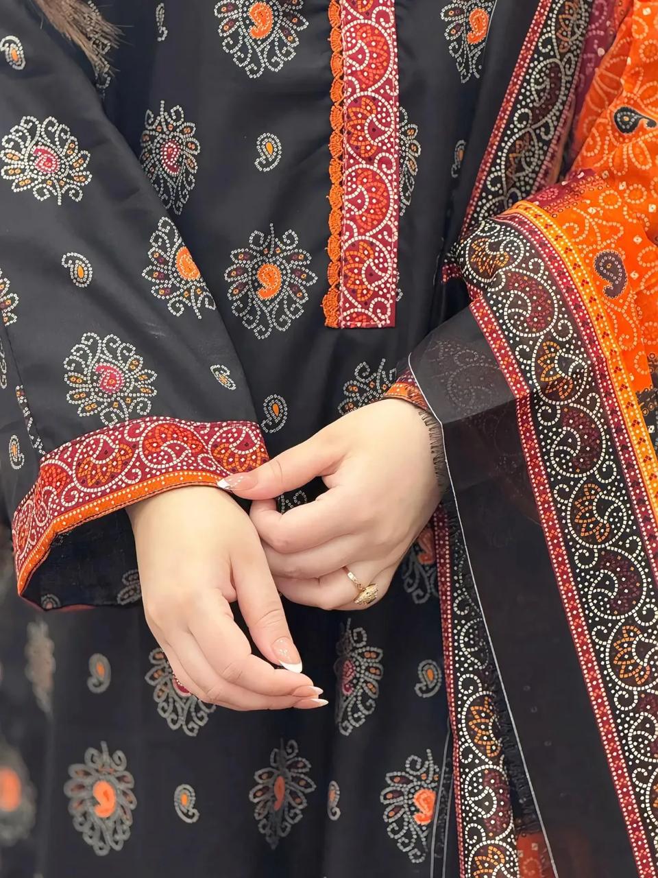 Close-up of a person wearing a black embroidered garment with orange and red details.