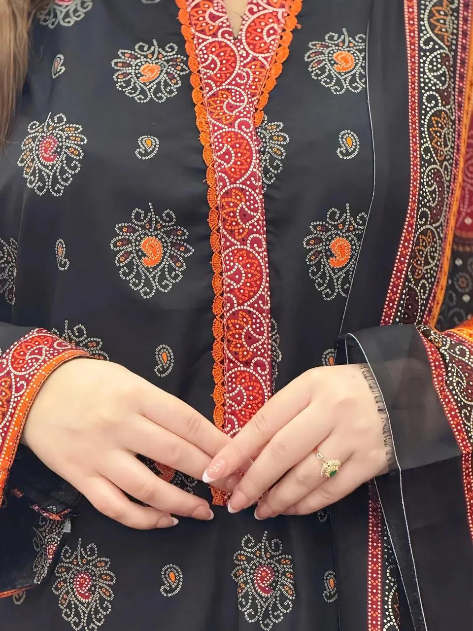 Close-up of a person wearing a dark blue embroidered garment with orange and white patterns.