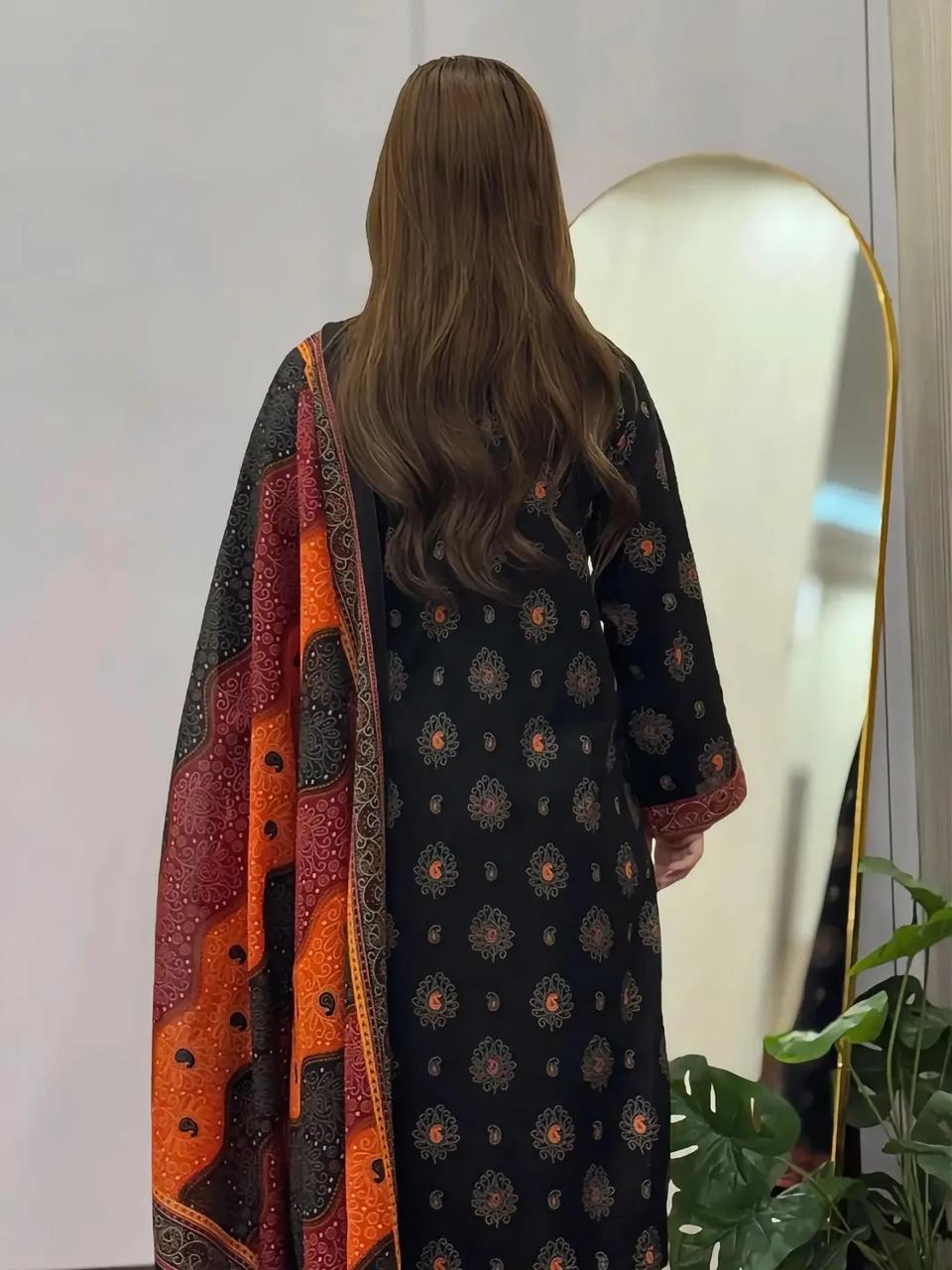 Person wearing a black patterned dress with orange accents, standing in front of a mirror.