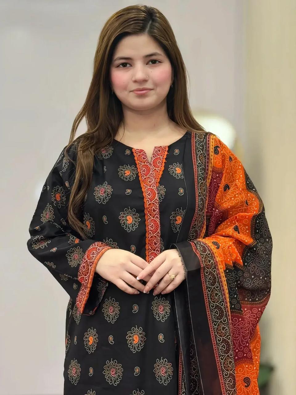 Woman wearing a black and orange traditional outfit with intricate patterns.