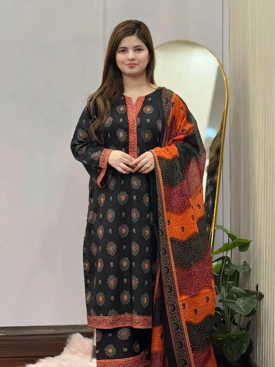 Woman wearing a black and orange patterned dress with a matching shawl indoors.