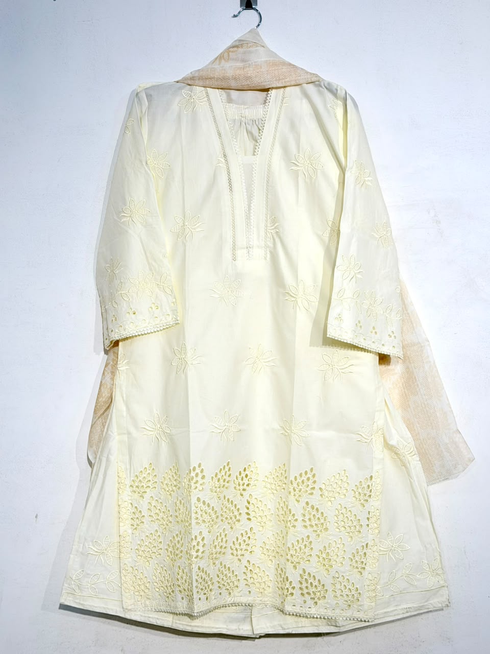 Light yellow embroidered dress on a hanger against a white background