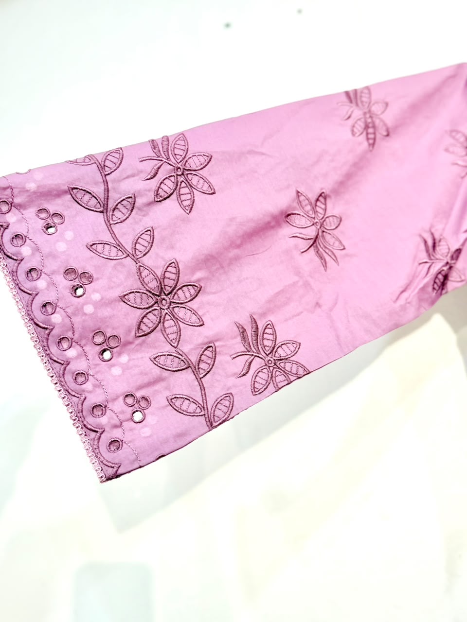 Pink fabric with floral embroidery on a white background