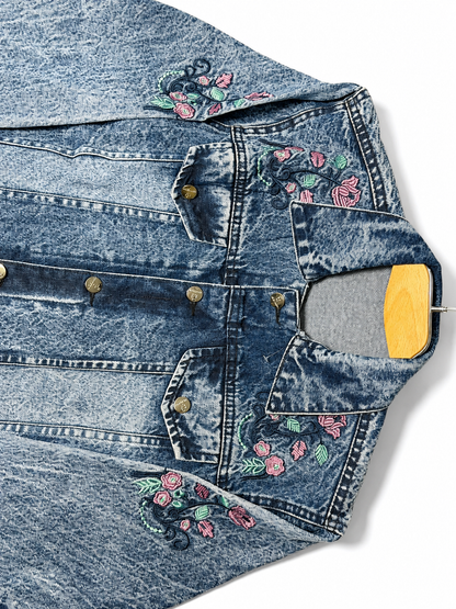Pink floral embroidery close-up on women's acid wash denim jacket