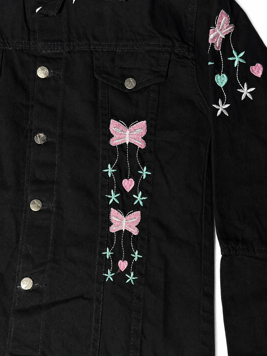 Pink bow and heart embroidery close-up on women's black denim jacket